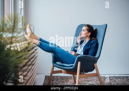 Thoughtful young businesswoman sitting on armchair Stock Photo