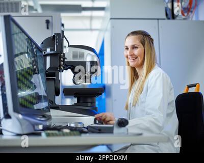 Happy technician working on computer at E-Laboratory Stock Photo