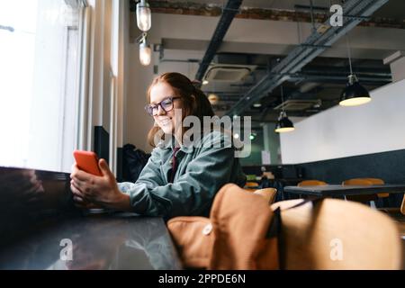 Smiling young freelancer using mobile phone in cafe Stock Photo