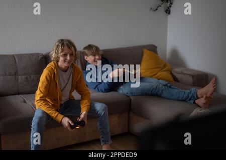 Happy boy playing video game with friend at home Stock Photo