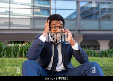 Surprised businessman with head in hands talking on mobile phone outside office building Stock Photo