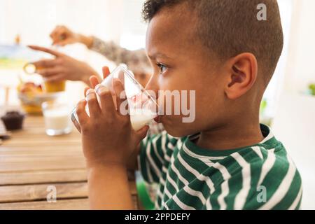 Boy drinking milk in glass at home Stock Photo