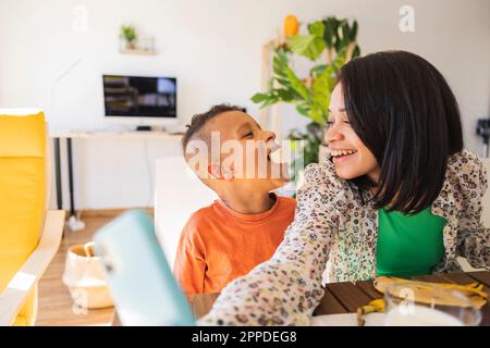 Happy mother taking selfie with son eating banana at home Stock Photo