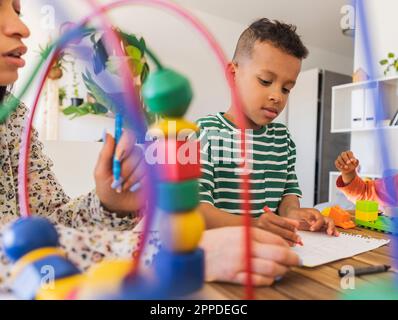 Mother helping boy in painting at home Stock Photo