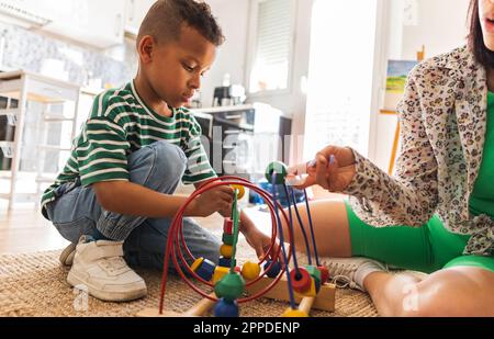 Mother assisting son in learning abacus at home Stock Photo