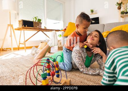Smiling mother playing with boys at home Stock Photo