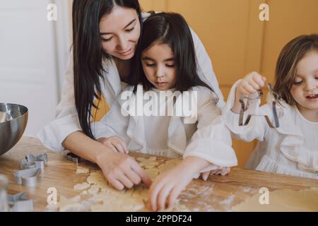 Mother helping daughters in making cookies for Easter Stock Photo