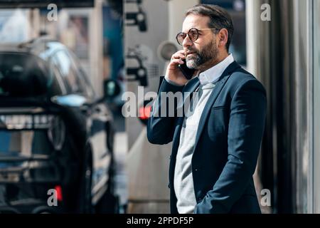 Businessman talking on smart phone standing at car wash Stock Photo