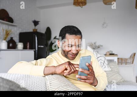 Smiling mature man using smart phone at home Stock Photo