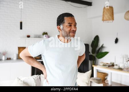 Mature man standing with hands on hip at home Stock Photo