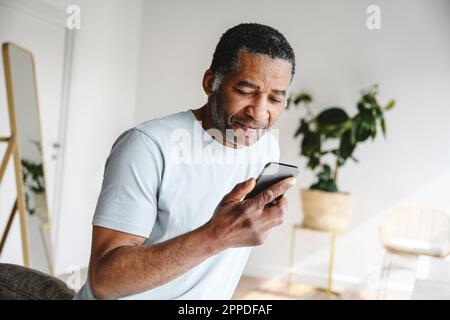 Mature man using mobile phone at home Stock Photo