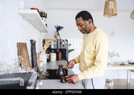 Mature man preparing coffee in kitchen at home Stock Photo