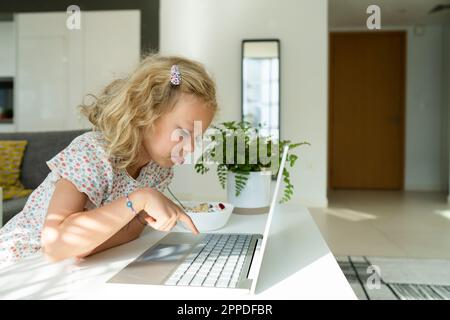 Blond girl typing on laptop at home Stock Photo