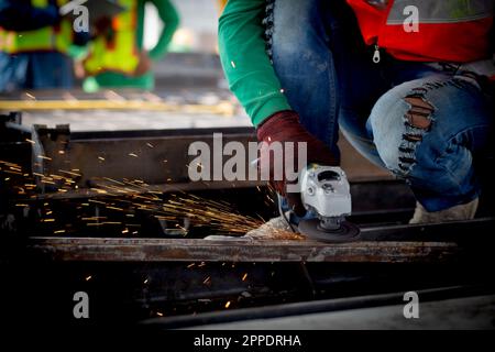 Closeup hands young asian worker using grinder cut iron with hands working in industrial factory, welder man or labor cut steel while having sparkle, Stock Photo