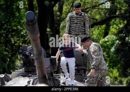 Bucharest, Romania. 23rd Apr, 2023. A Romanian soldier helps as a child steps on a tank at a static exhibition of military equipment marking Romanian Land Forces Day at a park in Bucharest, capital of Romania, April 23, 2023. Credit: Cristian Cristel/Xinhua/Alamy Live News Stock Photo