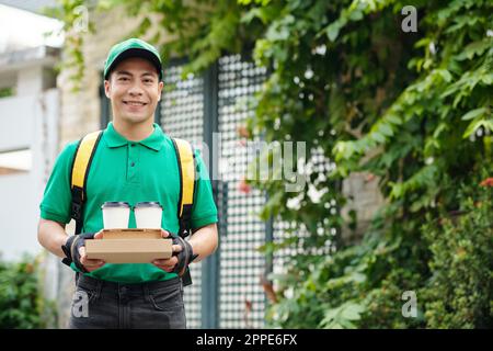 Smiling young man in uniform working as courier Stock Photo