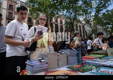 Barcelona, Spain. 23rd Apr, 2023. People look through books at the stalls during the day of 'Sant Jordi'. Every 23rd of April, Catalonia celebrates one of the most important traditions of the territory, the day of 'Sant Jordi'. On this day Catalonian people exchange books and roses with their loved ones. Love and literature are celebrated throughout Catalonia. (Photo by Axel Miranda/SOPA Images/Sipa USA) Credit: Sipa USA/Alamy Live News Stock Photo