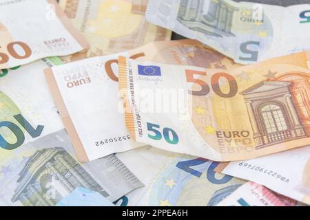 A close-up photo of various euro bills including 5, 10, 20, 50, and 100 denominations spread out on a table. Financial concept. Stock Photo