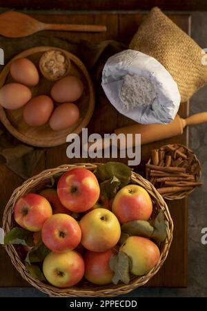 Top view on a ripe apples on a wooden table in basket with ingredients for pie near Stock Photo