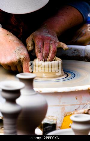 unrecognizable woman at street art workshop using a potter wheel, live handicraft a clay shell Stock Photo