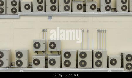 Many condensing units of air conditioners are installed on concrete building wall. Air conditioner maintenance and repair service at home or office. Stock Photo