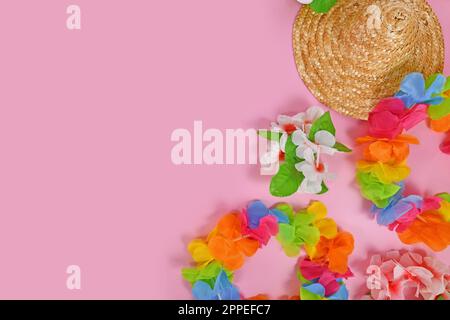 Bright flower lei necklaces and summer straw hat on side of pink background with copy space Stock Photo