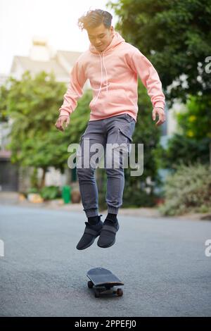 Active young man performing stunt, jumping on skateboard Stock Photo