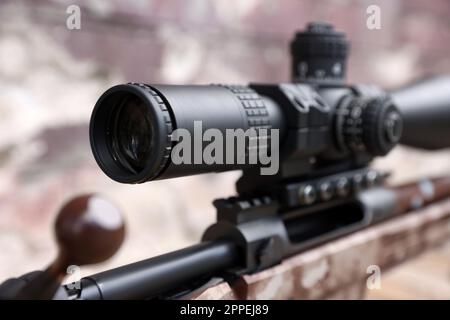 Closeup view of modern powerful sniper rifle with telescopic sight on blurred background Stock Photo