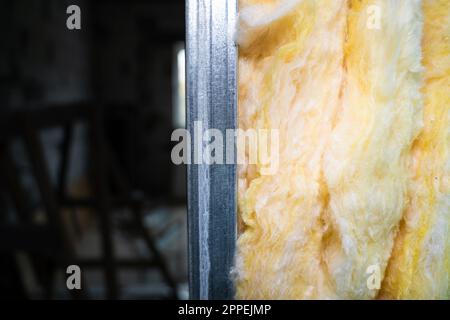 The partition is filled with glass wool close-up. Frame wall from a metal profile with mineral wool close-up on a blurred background Stock Photo