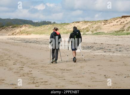 Two people enjoying a brisk walk at Dragey-Ronthon beach, Plage de la Dune, Normandy, North West France, Europe Stock Photo