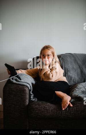 Girl on sofa using digital tablet Stock Photo