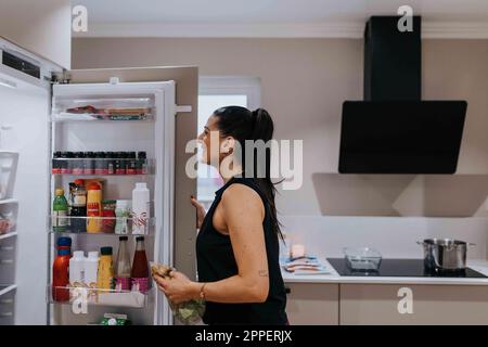 Woman standing in front of open fridge Stock Photo