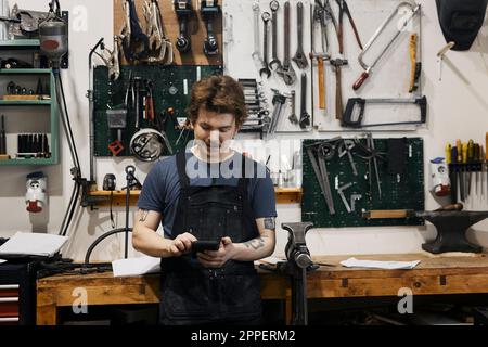 Blacksmith using smartphone in his workshop Stock Photo