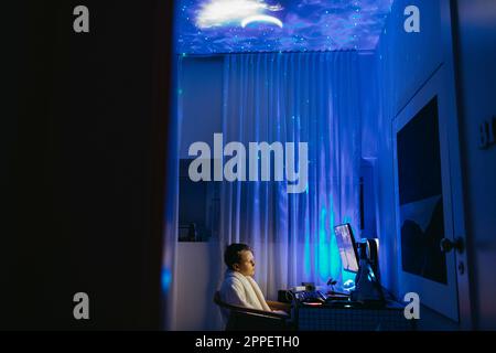 Boy at desk using computer at night Stock Photo