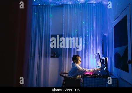 Boy at desk using computer at night Stock Photo