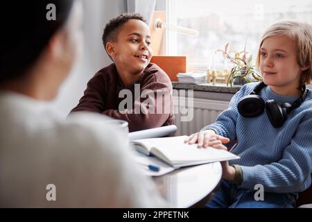Two boys doing homework at dining table Stock Photo