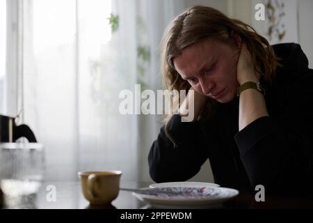 Sad woman sitting at table Stock Photo