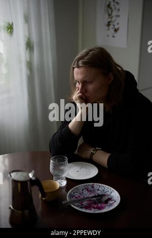 Sad woman sitting at table Stock Photo