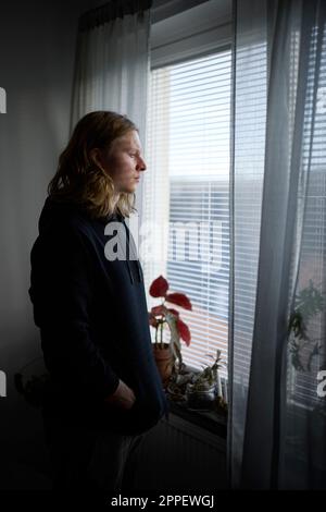 Sad woman looking through window Stock Photo