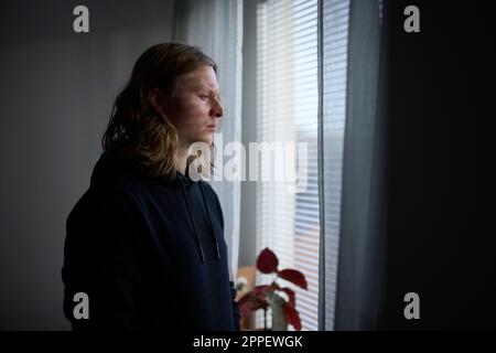 Sad woman looking through window Stock Photo