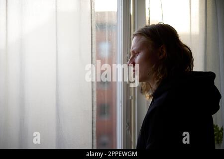 View of woman looking through window Stock Photo