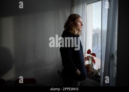 Sad woman looking through window Stock Photo