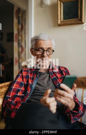 Senior man using smart phone at home Stock Photo