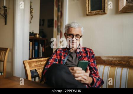 Senior man using smart phone at home Stock Photo