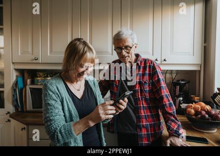 Senior couple using smart phone at home Stock Photo