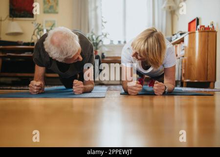 Senior couple doing planks at home Stock Photo