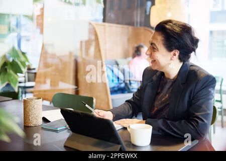 Smiling businesswoman sitting in cafe Stock Photo