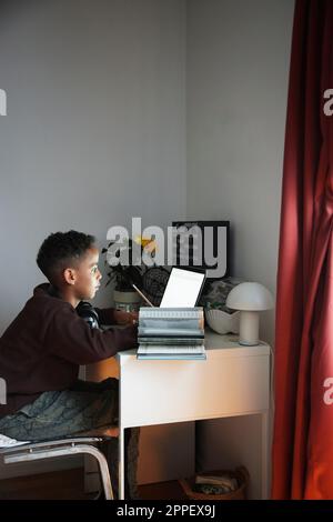 Boy doing homework with laptop Stock Photo