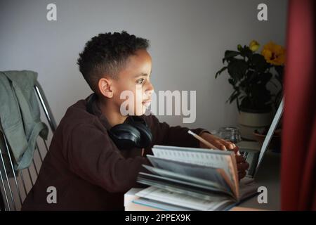 Boy doing homework with laptop Stock Photo