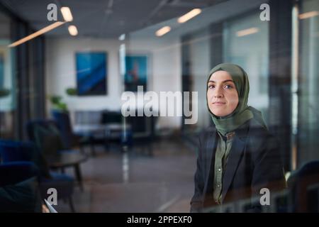 Woman in headscarf looking through window Stock Photo